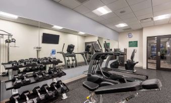 a gym with various exercise equipment , including treadmills and weight machines , arranged in an open space at Wingate by Wyndham Angola