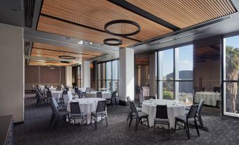 a large , modern dining room with several round tables and chairs arranged for a formal event at Vibe Hotel Melbourne Docklands