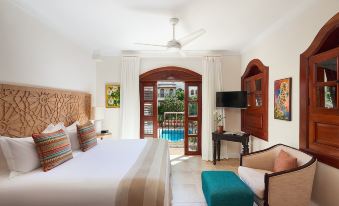 a luxurious hotel room with a king - sized bed , a television , and a balcony overlooking a swimming pool at Cap Maison Resort & Spa