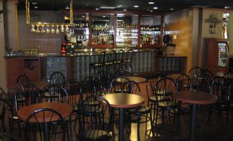a dimly lit bar with wooden tables and chairs , along with a bar counter stocked with liquor bottles at DoubleTree by Hilton Claremont