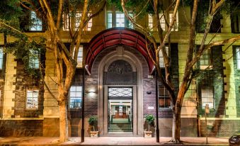 the entrance to a building with an arched doorway and tree trunks on either side at Oaks Sydney Goldsbrough Suites
