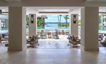 a room with a view of the ocean through a glass window , surrounded by chairs and tables at Shangri-La le Touessrok, Mauritius