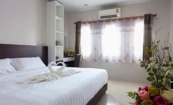 a clean and well - organized bedroom with a white bed , white curtains , and a window with flowers at Belleville Hotel