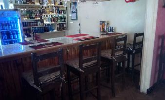a bar with wooden stools and chairs , along with a counter and shelves filled with bottles at Spice Garden