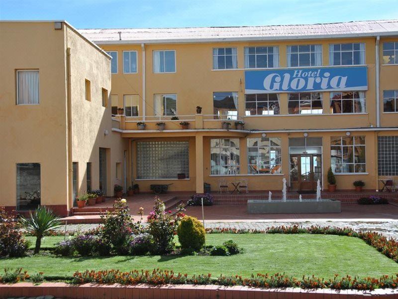 "a large building with a sign that says "" hotel gloria "" on it , surrounded by a grassy area and trees" at Copacabana