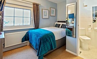 a modern bedroom with blue walls , white curtains , and a bed dressed in blue bedding at The Pytchley Inn