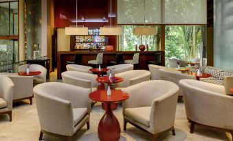 a modern , well - lit lounge area with several beige chairs and red tables , creating a comfortable and inviting atmosphere at Mercure Iguazu Hotel Iru