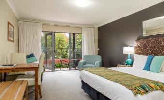 a bedroom with a large bed , blue chair , and sliding glass door leading to an outdoor patio at Berry Village Boutique Motel