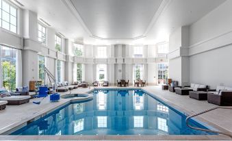 an indoor swimming pool with a large , empty space and several chairs surrounding it , creating a relaxing atmosphere at Hilton Columbus at Easton