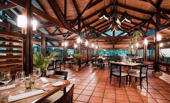 a large restaurant with multiple dining tables and chairs , some of which are occupied by people at Tabacon Thermal Resort & Spa