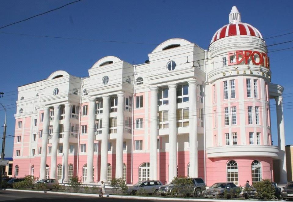 a large pink and white building with a dome on top , surrounded by trees and parked cars at Hotel Europe