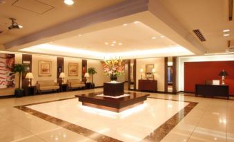 a large , well - lit hotel lobby with white walls and a marble floor , featuring a reception desk and several potted plants at Hotel Hokke Club Hiroshima