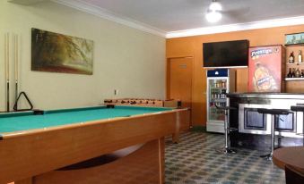 a pool table is in the foreground of a room with a vending machine and a television on the wall at Hotel La Cretonne