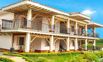 a large white building with a balcony and a green lawn in front of it at Hotel Campestre las Camelias