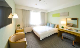 a well - lit hotel room with a large bed , two chairs , a desk , and a window at Hotel Resol Machida