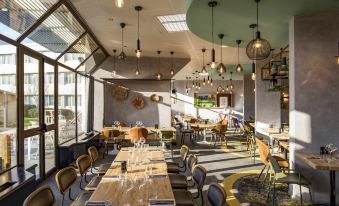 a modern restaurant with wooden tables , chairs , and pendant lights , as well as a bar area at Novotel le Mans