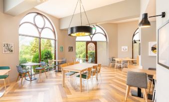 a dining room with wooden floors , large windows , and a hanging light fixture over the table at Holiday Inn Gloucester - Cheltenham
