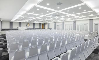 an empty conference room with white chairs arranged in rows and a large screen on the wall at Hotel Frontera Clasico