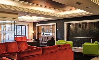 a modern office space with a large window , black ceiling , and red sofas arranged in a living room area at Prince of Wales Hotel