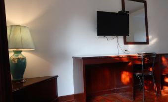 a desk with a lamp and chair in front of it , and a television mounted on the wall above the desk at Triple Resort