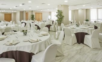 a large banquet hall with multiple round tables covered in white tablecloths and chairs arranged for a formal event at Hesperia Vigo