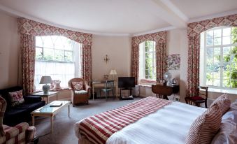 a large bedroom with a bed , chairs , and a television in front of windows at Castle Hotel