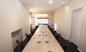 a long wooden conference table with chairs and a white projection screen in the background at Domaine la Pierre Blanche