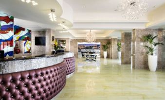 a large hotel lobby with marble floors , a curved reception desk , and several chairs arranged around it at Swan River Hotel