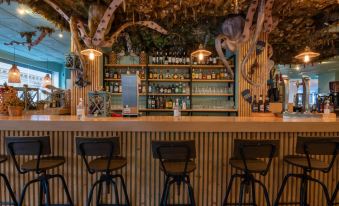 a bar with a wooden counter and stools , surrounded by shelves filled with various bottles and glasses at Sercotel Hotel Bahia de Vigo