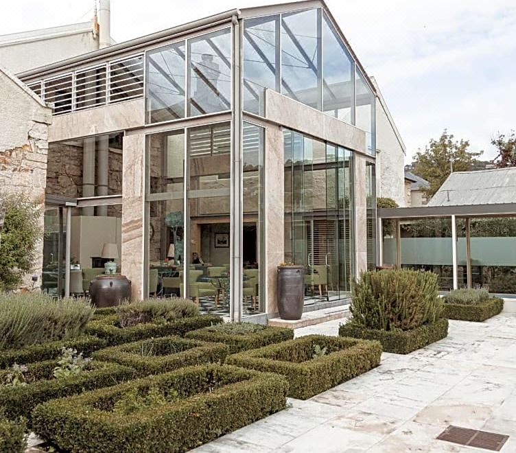 a modern glass house with a stone patio and garden , surrounded by other buildings and greenery at Islington Hotel