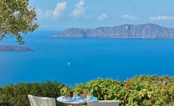 a table with two chairs is set up on a balcony overlooking the ocean , overlooking mountains and boats at Belvedere Suites