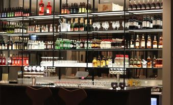 a well - stocked bar with various bottles and glasses on shelves , as well as a dining table in the background at Hotel Odeon