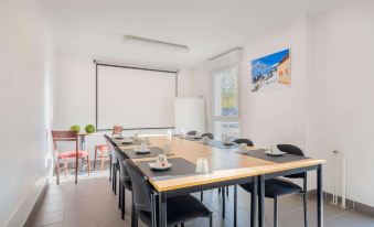a conference room with a long table , chairs , and a projector screen , set up for a meeting or presentation at Comfort Suites Pau Idron