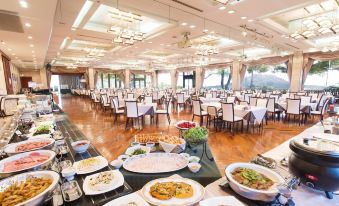 a large dining room filled with tables and chairs , where people are enjoying a meal at SHIROYAMA HOTEL kagoshima