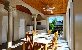 a dining room with a wooden table and chairs , a ceiling fan , and a window at Windarra on High