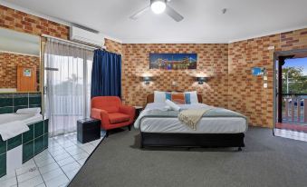 a cozy bedroom with a large bed , a red chair , and a door leading to a balcony at Airport Clayfield Motel