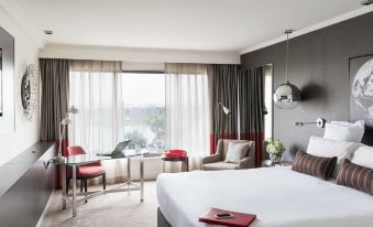 a modern hotel room with a large bed , desk , and chairs near a window overlooking the city at Pullman Melbourne Albert Park