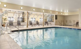 an indoor swimming pool surrounded by chairs and lounge chairs , with a spa in the background at Homewood Suites by Hilton Columbus - Hilliard