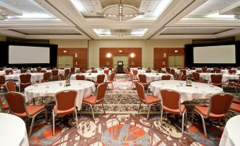 a large conference room with tables and chairs arranged for a meeting or event , surrounded by screens and a podium at Embassy Suites by Hilton Chicago Downtown Magnificent Mile