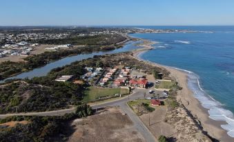 aerial view of a residential area near the ocean , with a boat docked on the shore at Seaspray Beach Holiday Park
