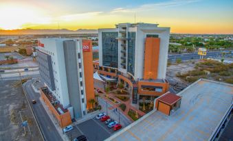 a bird 's eye view of a large building with an orange and white facade , surrounded by a parking lot at Ibis Torreon