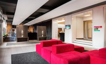 a modern hotel lobby with a red couch and chairs , as well as a reception desk at Park Inn by Radisson Katowice