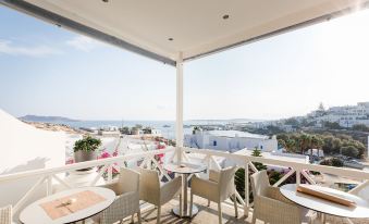 a balcony with white furniture and a view of the ocean , under a clear blue sky at Paliomylos Spa Hotel