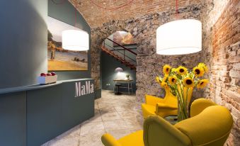 a modern office space with yellow and green furniture , including chairs , a reception desk , and potted plants at MaMa