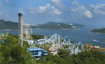 There is an amusement ride on top of a large park with water and mountains in the background at Rosedale Hotel Hong Kong