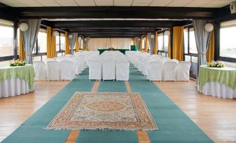 a large room with a long table and chairs , a rug on the floor , and windows at Hotel L'Approdo