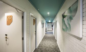 a long , white - tiled hallway with green ceiling and walls , leading to a door at the end at Nightcap at Playford Tavern