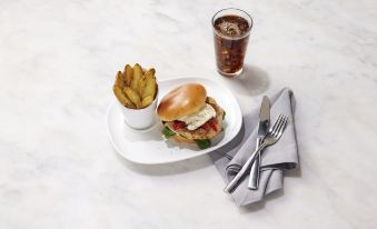a white plate with a burger , fries , and a cup of soda on a dining table at Even Hotel Rockville - Washington, DC Area, an IHG Hotel