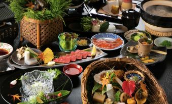 a large dining table filled with a variety of food items , including meat , vegetables , and fruits at Miyako