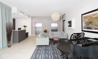 a modern living room with a large chandelier , gray and white sofa , black coffee table , and black stool at Quest Highbrook